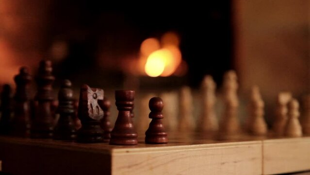 Chess game set up on a table in front of a burning fire