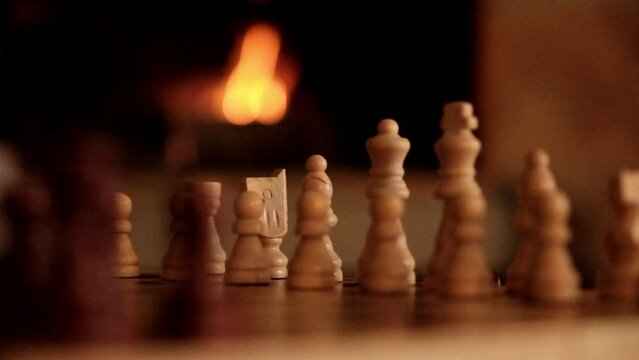 Chess pieces set up for a match in front of a fire