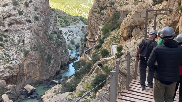 People hiking with helmets the famous caminito del rey between mountain cliffs in Malaga, Spain
