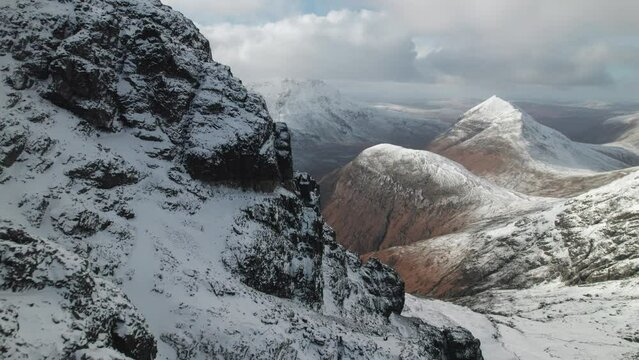Drone tilt shot of Bla Bheinn mountain in winter. Snowy cliffs and peaks of Cuillin range in Isle of Skye, Scotland.