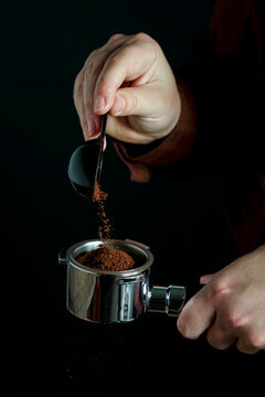 barista pours ground coffee into coffee portafilter