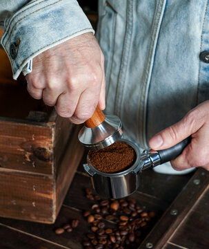 Barista hold portafilter and coffee tamper make coffee in coffee shop or cafe, dark backgrounds