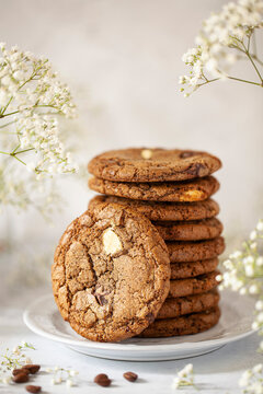 A stack of chocolate chip and coffee flavoured cookies with one leaning against the side of the stack. of coffee cookies wi