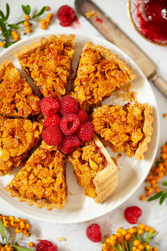 A sliced up cornflake tart served with fresh raspberries.