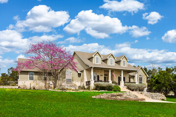 a traditional  home with a green lawn and cherry blossoms