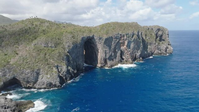 Aerial view of LA PUERTA CAVE in CABO CABRON National park with Clouds at sky - Waves crashing against rocky coastline 