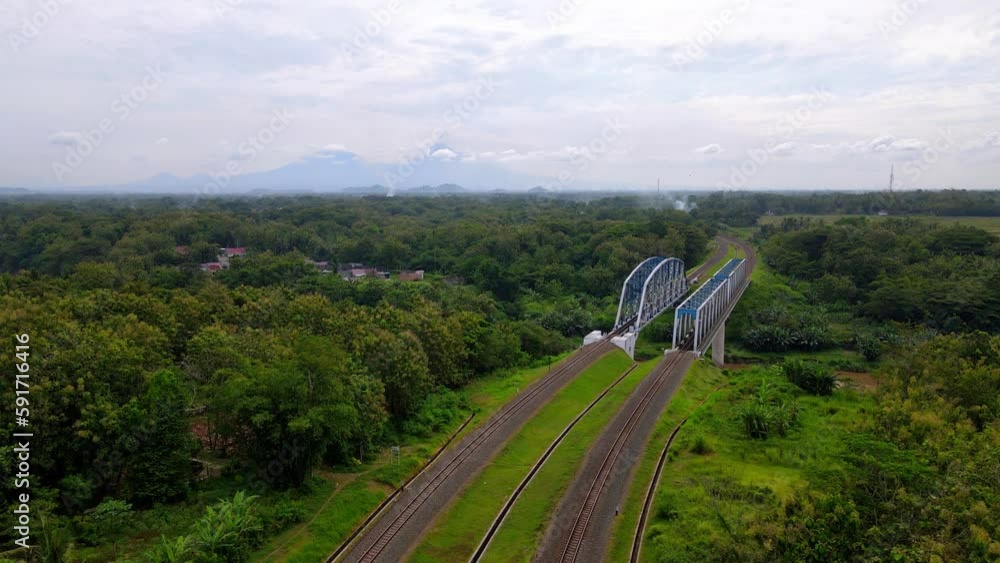 Poster drone view of train rail and bridge over river in rural magelang, central java