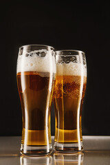 Golden brew with foam, bubbles filling tall glasses.