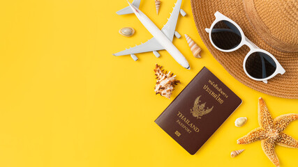 Summer time and travel concept, top view of passport and airplane, sunglasses on hat with starfish on yellow background.