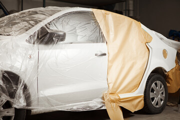 Body repair of the car after the accident. Wraping of vehicle with protective paper before painting.