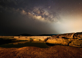 waterfront, rocks, drought At night, there are stars, constellations, the Milky Way in the background.