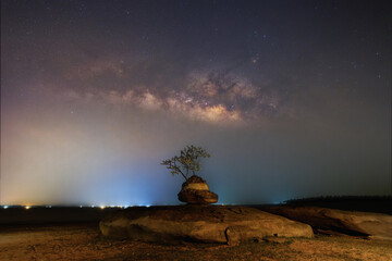 Giant rock at night with stars, constellations, milky way in the background.