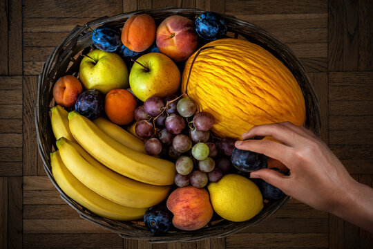 The human hand takes fruit from a basket.