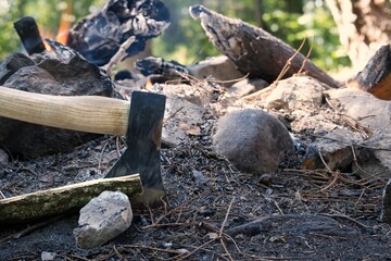 Camp fire in a forest with chopper in wood
