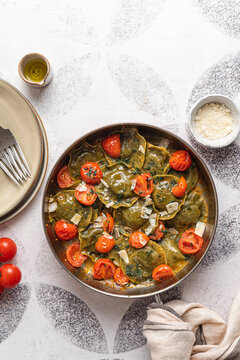 Spinach and broccoli vegan ravioli with cherry tomatoes on a white background
