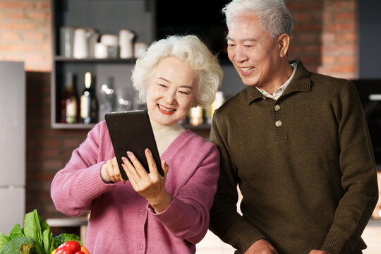 Elderly couple using tablets for cooking