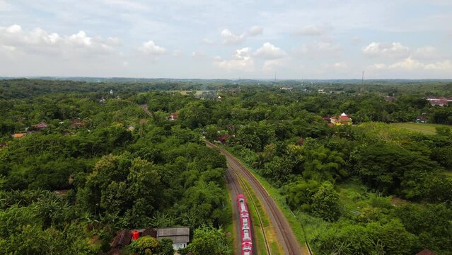 Aerial view of a train running on rails with view of the beautiful rural landscape . The train rides through rural countryside in cloudy weather. train rides along the beautiful summer - Drone footage