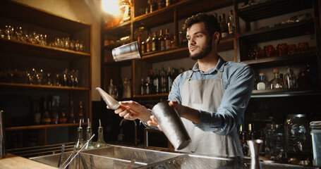 Authentic professional caucasian bartender flaring his shaker before making a cocktail. Experienced...