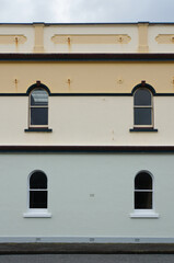 Four arched windows in a pastel-coloured building facade