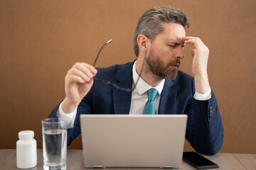 Business man feel pain holding glasses rubbing dry irritated eyes fatigued from computer work, stressed man suffer from headache bad vision sight problem sit at office. Deadline and stressed job.