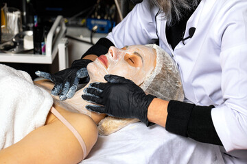 Facial cleansing procedure for a young woman in a spa salon.