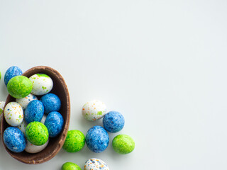 Sweet Easter concept. Blue, white and green chocolate easter eggs with sweets on white background with copy space. Design for a greeting card for the Easter holiday. Flat lay. Preparation for holiday