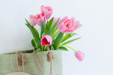 Pink tulips bouquet in green shopping bag on white background copy space