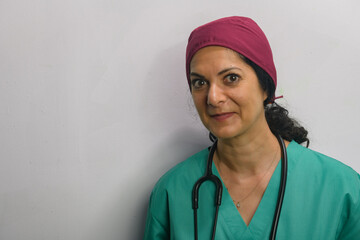 Health professional poses in studio against a grey wall, wearing green scrubs.