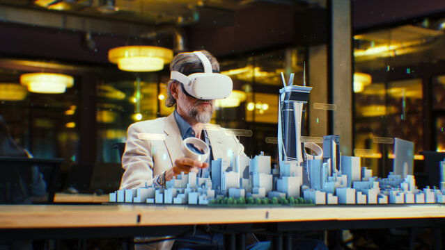Male engineer uses VR headset and wireless controllers, creates architectural project of the city in virtual reality. Man works in modern hi-tech company. 3D hologram. Future digital AI technologies.