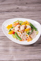 stir fried white shimeji mushroom with scallop black fungus cashew nut deep fried yam bean curd and mixed colourful vegetables on wood table asian Chinese vegan halal food banquet menu for restaurant