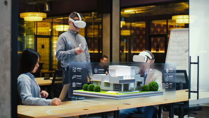 Male designer uses VR headset and wireless controllers, presents smart home exterior design project in virtual reality to coworkers. Modern hi-tech company. 3D hologram. Future digital technologies.