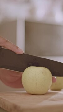 person cutting apple on kitchen board, upright, 9:16