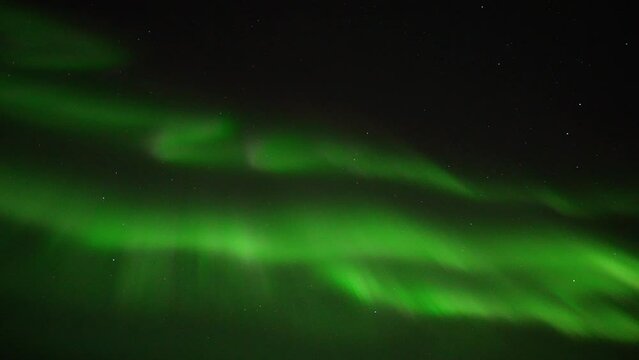Green Aurora Borealis moving slowly against dark sky at night - Wide shot