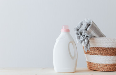 Washing gel liquid laundry detergent and fabric softener, basket with towel on a wooden table...