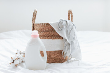Washing gel liquid laundry detergent and fabric softener, basket with Peshtemal towel on white bed...