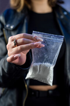 female hand wear dark clothes holds bag with cocaine . narcotic