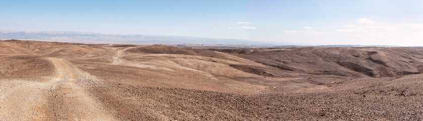 extra wide Panorma of an extremely arid desert area in the Arava Region of the Negev Desert in Israel with the Syrian African Rift and Jordanian mountains in the background