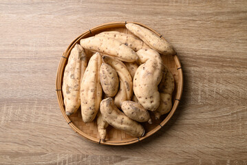 Organic Asian white sweet potatoes in basket on wooden background, Table top view