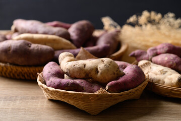 Organic Asian sweet potatoes in basket on wooden background