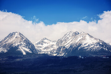 Fototapeta na wymiar nature background of mighty high tatra ridge in spring at high noon. snowcapped rocky peaks beneath a cloudy sky