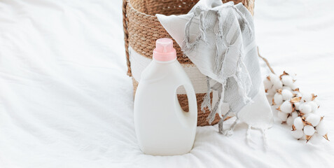 Washing gel liquid laundry detergent and fabric softener, basket with Peshtemal towel on white bed...