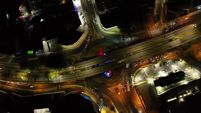 A beautiful aerial drone view of the nightly traffic at San Pedro Highway, Costa Rica. Rising pedestal and rotation movement, camera looking down.
