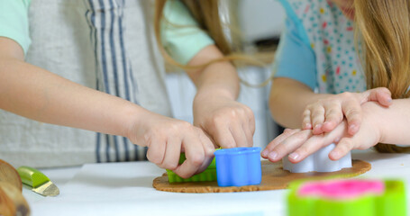 Obraz na płótnie Canvas Children's hands cut out a shape for cookies on rolled out dough