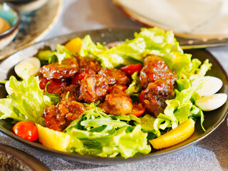 a plate of hot salad with caramelized meat.
