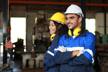 Group of technician engineer in protective suit standing and arm crossed while looking camera and controlling or maintenance operation work lathe metal machine at heavy industry manufacturing factory