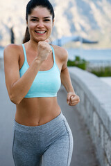 Fototapeta premium Healthy lifestyle sport people concept. Happy fit woman running on sunrise seaside outdoors.