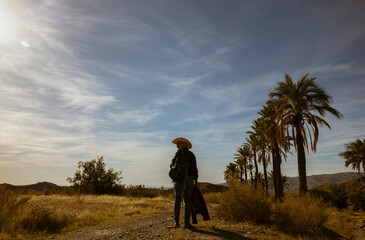 Rear view of adult man in cowboy hat walking on desert. Almeria, Spain