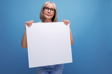 retired woman with gray hair holding blank billboard with mocap on studio background