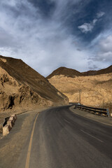 Curvy metal road winds through stunning Moonland Mountains in Ladakh near Lamayuru, offering breathtaking views.