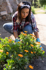 Pretty Latin woman taking care of garden plants on a bright spring day